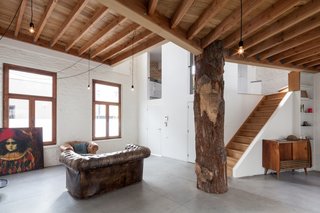 Large wood-framed windows flood the interior with natural light while openings in the walls give the home a porous character.