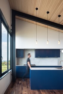 The kitchen is outfitted with Caesarstone counters and is completed with blue-painted walnut plywood cabinets.