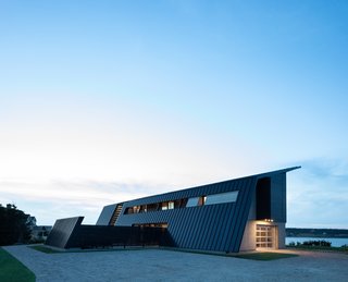 Extra-dark bronze standing-seam metal partly clads the home and creates an armored appearance.