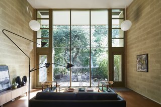 The east side of the living space opens up to a spectacular double-story wall of glass framed by vertical wood mullions and horizontal aluminum H-channels. A six-foot roof overhang protects the glazing from solar gain.