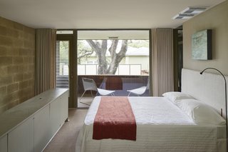 Located above the kitchen and dining area, the loft bedroom includes a walk-in closet, bathroom, and access to the second-floor balcony, which is framed by full-height glazing.