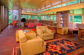 The living room and dining area features original built-in seating, tables, and chairs designed by Frank Lloyd Wright.