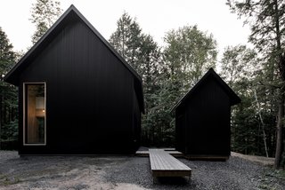 A pathway winds through the woods from the parking pad to reveal the cottage and a raised cedar walkway.