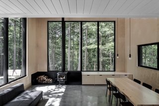 A view of the dining area and living space from the kitchen. The floors are polished concrete while the walls are lined in baltic birch. The lighting is by Hamster.