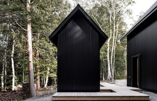 The home also includes a small outbuilding that echoes the main building's monochromatic, gabled form.