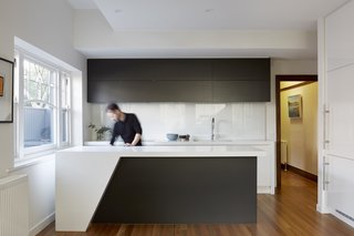 The modern kitchen features Caesarstone "Snow" counters and cabinets with a two-pack polyurethane finish. The appliances are mainly by Miele.