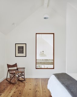 The master bedroom with reclaimed longleaf pine floors overlooks views of the living space. The chair was a gift from Sarah’s mother and the art was gifted by Casey’s parents.