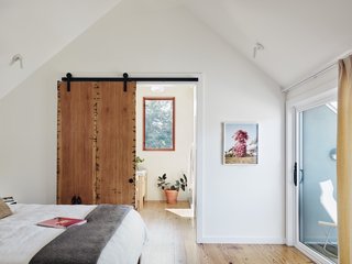 A sliding barn door built of salvaged pine separates the master bedroom from the bath.