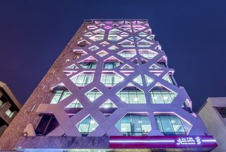 The two skins are spaced approximately two a half feet apart, creating room for the installation of LED backlighting that illuminates the building like a beacon at night. The combination of blue lighting and the patterned facade are evocative of Persian blue mosaic work.