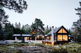 The timber decking that connects the existing cottage to the new volumes emphasizes indoor-outdoor living.
