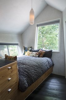 The cozy one-bedroom overlooks views of the tree canopy. For small bedroom ceiling lighting ideas, we love this simple, cylindrical pendant light that offers just the right amount of soft light. 