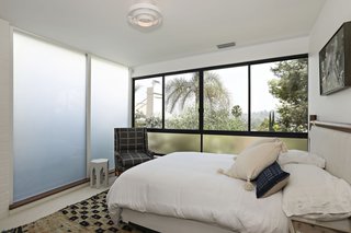 This guest room gets drenched in sunlight thanks to full-height frosted glass windows and operable glazing overlooking the city below.