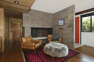 Behind the bright red entrance door is a concrete block fireplace and a snug den.