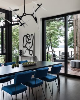 The dining room features a striking Agnes 10-light chandelier by Lindsey Adelman for Roll & Hill. Below, a Montis Doble table is combined with vintage Case Study iron chairs upholstered in blue fabric. The artwork, titled <i>Linger</i>, is by Kate Neckel via Winston Wächter.