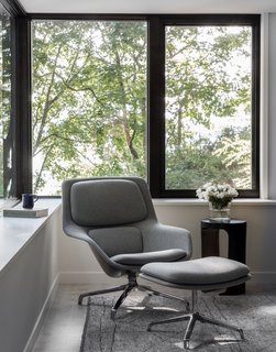 The sun room, located between the kitchen and outdoor deck on the main floor, is furnished with a Herman Miller Striad lounge chair from DWR, an Odyssey rug from Driscoll Robbins, and a Kade accent table from Arteriors.