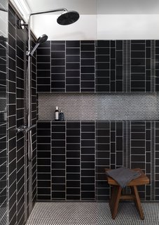 A custom mix of graphite tiles from Ann Sacks line the walls of the master bath. The floors are white penny rounds from American Universal Corporation.