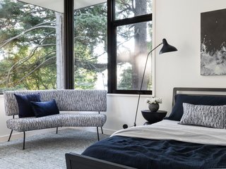 Bathed in natural light, the master bedroom is tastefully decorated. The vintage sofa has a Hable Construction Horsehair cover from HM Duke Design. The Woodrow bed in Smoke by Blu Dot is dressed in West Elm linens. The Mantis BS1 B floor lamp is from DWR, and the custom wool rug is from Driscoll Robbins.