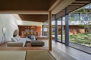 "Although the LDK (living room, dining room, kitchen) faces east, it is bathed in light reflected off the hill in the afternoon," says the architect. "With the absence of beams and sealing strips, the rafter seems to protrude from the white structural wall, making the LDK seem like a semi-outdoor veranda. The living room has become part of the garden, where you can naturally engage with the children playing or sprawling on the slope of the hill."