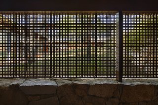 The lath screen offers a glimpse of the grassy hill from the entryway.