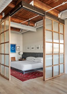 Sliding walnut panels with reeded glass inserts enclose the bedroom area.