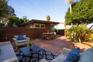 A rear deck added in 2009 offers ample outdoor entertaining space. Here, the deck is anchored with an outdoor sofa set from Cost Plus World Market, while an outdoor dining set sits closer to the house.