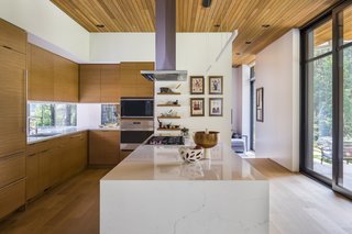 The sleek kitchen is fitted with a Miele dishwasher, Miele oven, Wolf Cooktop, and Sub-Zero refrigerator. The cabinetry is white oak.