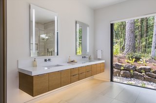 Mosa porcelain tile lines the bathroom floors. Pictured here is the ground-floor master bath, with massive walls of glass framing forest views.