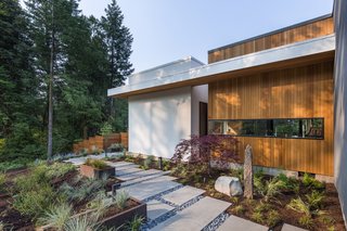 A view of the outdoor walkway that connects the patio to the master bedroom. The exterior is clad in traditional stucco and tongue-and-groove vertical cedar siding.