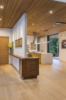 The entry leads directly to the open-plan kitchen, dining area, and living room, where full-height sliding doors extend the living spaces to the outdoors.