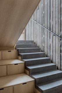 Poured concrete stairs step down alongside built-in storage.