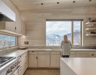 The oversized kitchen window frames spectacular views of Snowmass. Matching the white oak palette are pale Caesarstone countertops.