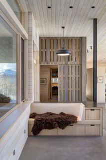 At the entry, a glimpse of the mudroom with the vertical-slat sliding door open.