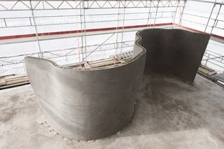 With the metal mesh manually filled in with concrete, the curvaceous load-bearing structure pictured here will be used for the living room wall.