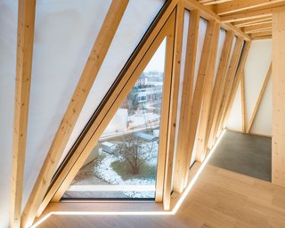 Angular windows punctuate the translucent facade, framing views of the outdoors and bringing in additional natural light.