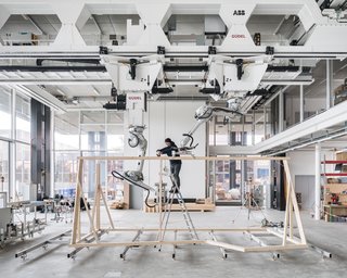 A team member manually bolts timber beams together for a prefab module.
