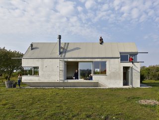 Collectif Encore designed the house for energy efficiency. It's composed of LECA blocks, which provide superior thermal insulation. The facade is plastered light gray, and the roof is made from wood.
