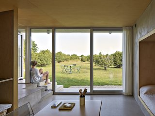 On the ground floor, this multifunctional room serves as a studio, a guest room, and a laundry room. The floor above holds the main bedroom, the main bath, and a workspace.