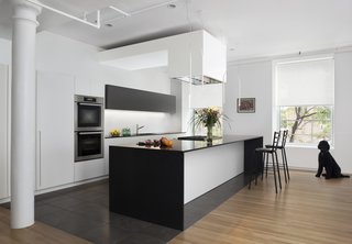 The architects reconfigured the kitchen layout so that it is open to the main living and dining area. The new finishes included white oak flooring, painted wood millwork, and stone counters.