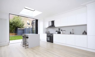 These 30 White Kitchens Are Anything But Ordinary - Photo 11 of 30 - "The ground floor layout and kitchen have been designed for simplicity and functionality. The dark weathered zinc on the exterior communicates with the blacks, whites, and grays of the interiors. However, the design of the interior achieves a softer touch by using bespoke detailing and a rich palette of materials such as stone and timber," says the architect.