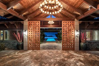 Designed by architect Robert Robinson after a Balinese resort, this Hawaiian estate commands sweeping ocean and multi-island views. The pool is visible, even from the custom front doors, which give off a warm, local vibe through their woven appearance and wood construction.