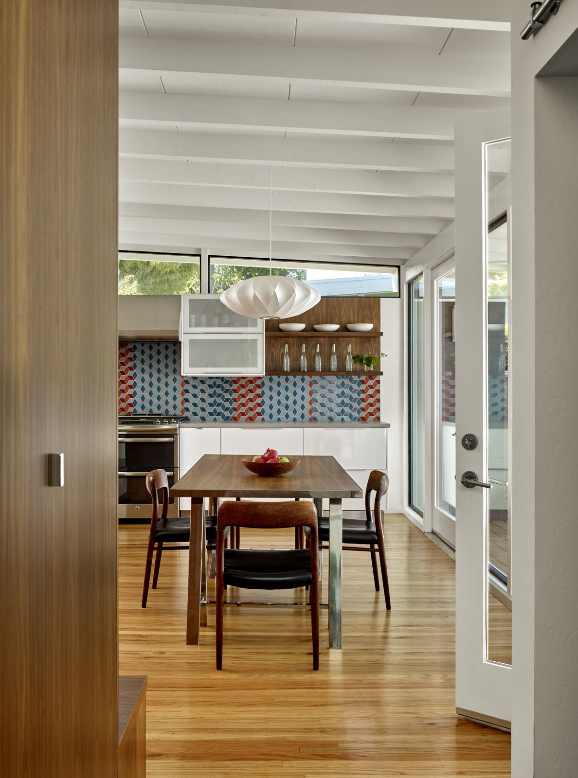 Custom walnut built-ins offer hidden storage along one side of the hallway.