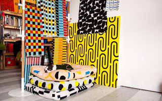 Dozens of examples of her brightly colored graphic prints are on display in some form — a rack of silky dresses, linen jumpsuits, and color-blocked jackets from her spring collection greet guests as soon as they walk in; a stack of dog beds, usually occupied by her Boston terrier, Snips, is in one corner, across from a pile of patterned and embroidered throw pillows; shelves are stacked with graphic bath and beach towels, fruit-printed bed linens and cozy blankets; poster boards of some of her most loved prints are both hung and leaning against any available wall space.
