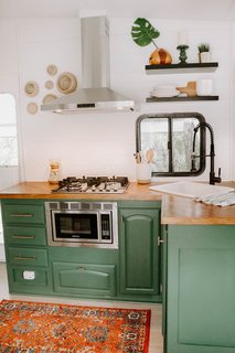 The biggest changes were made to the kitchen. Here, they removed all the cabinets in the upper section and added open shelving, a vent hood, a backsplash of white hexagon tiles, and lovely gold accents.