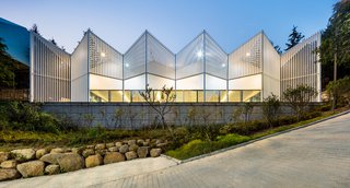 The community facility is formed of geometric shapes featuring white louvres made from steel. 