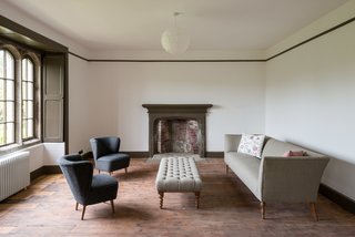 The picture rail and skirting board painted in khaki green frame the space, while the neutral walls make the trio of arched stone windows the standout feature of the room.