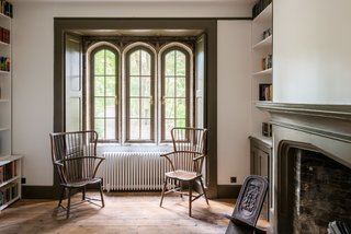 The wooden Windsor chairs placed by the recessed shuttered windows in the study create a cozy reading corner.