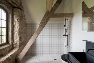 Monochrome, industrial, and minimalist, the utilitarian look of the bathroom fittings accentuate the building's rustic architectural features.
