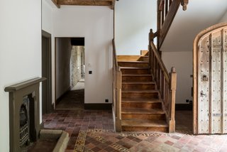 The oak staircase, arched studded front door, and decorative floor tiles in the hallway have a wonderful handcrafted look.