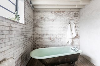 Housed underneath the mezzanine level, the bathroom features whitewashed walls and an elegant, freestanding bath.