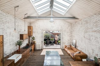 The mezzanine bedroom has elevated views across the living space, the decked terrace, and the city skyline beyond.